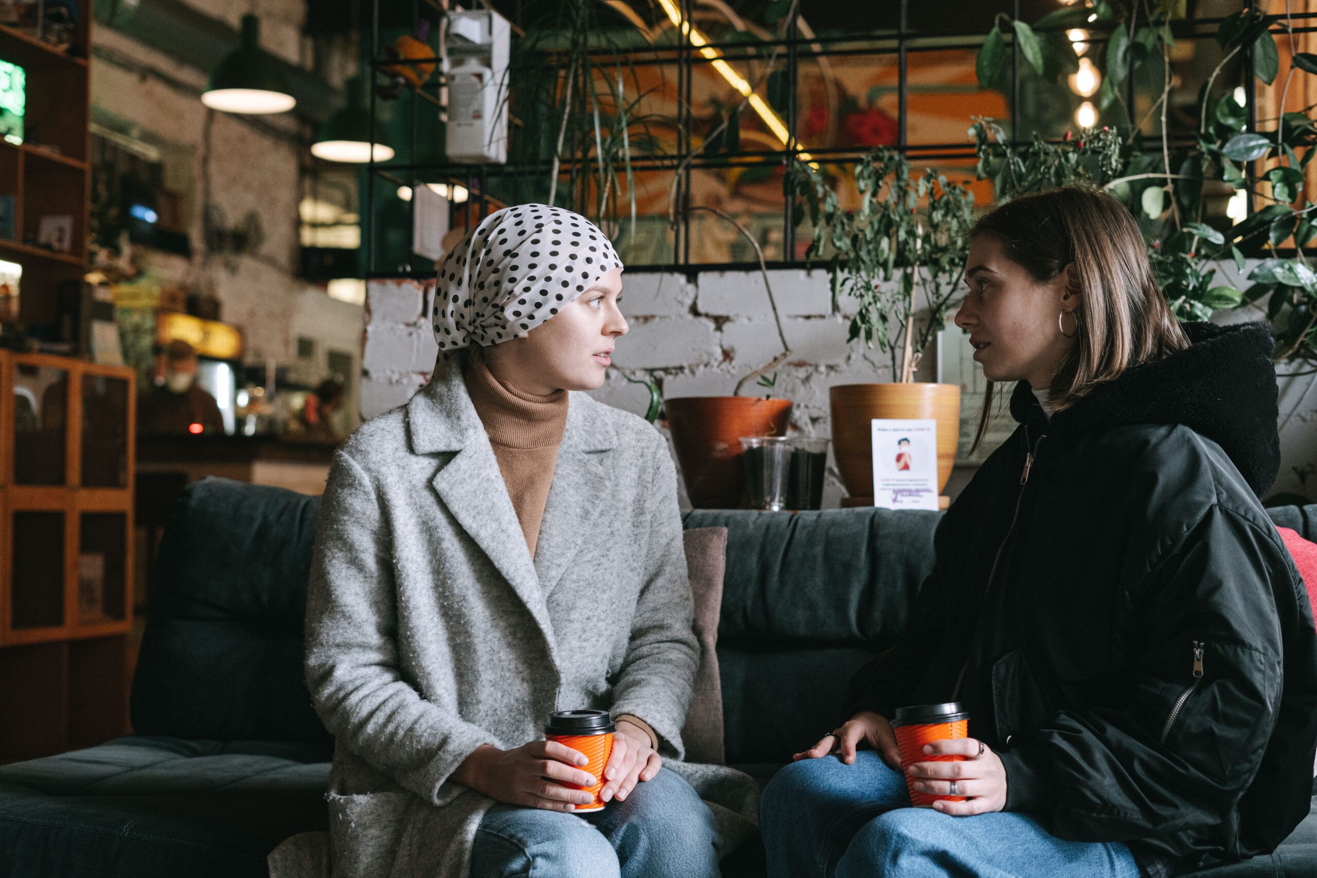 Two women sitting together with cups of tea, one offering comfort and support to the other